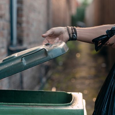 Persona Depositando Una Bolsa De Basura En Un Contenedor