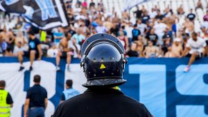 Policía observando una tribuna con hichas de futbol cantando